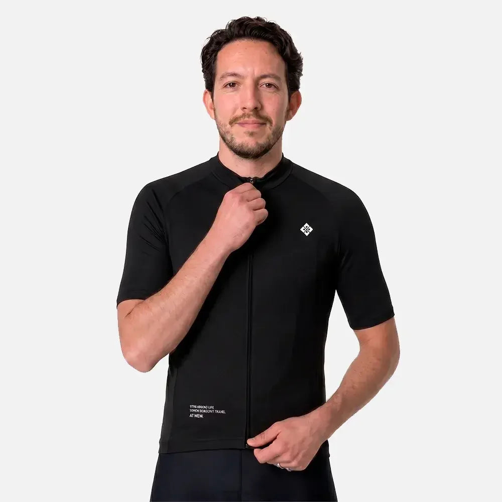 Man wearing black cycling jersey with zipper and logo, showcasing athletic fit and design.