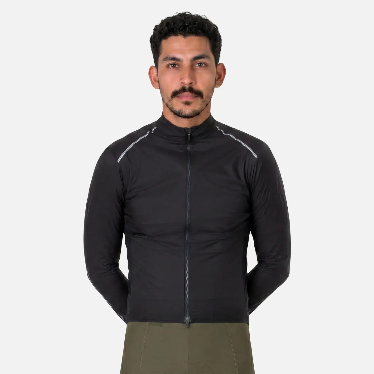 Man wearing black athletic jacket with reflective stripes and olive green pants